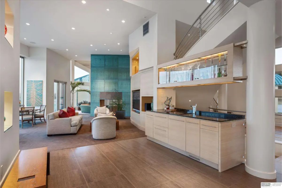 Open-concept living area featuring a cozy seating arrangement, built-in bar, and a unique green feature wall with a fireplace. 