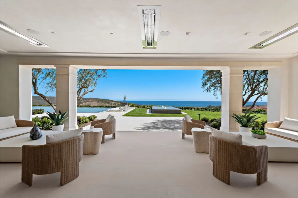 Expansive covered patio with comfortable seating, overlooking a stunning infinity pool and ocean view. 