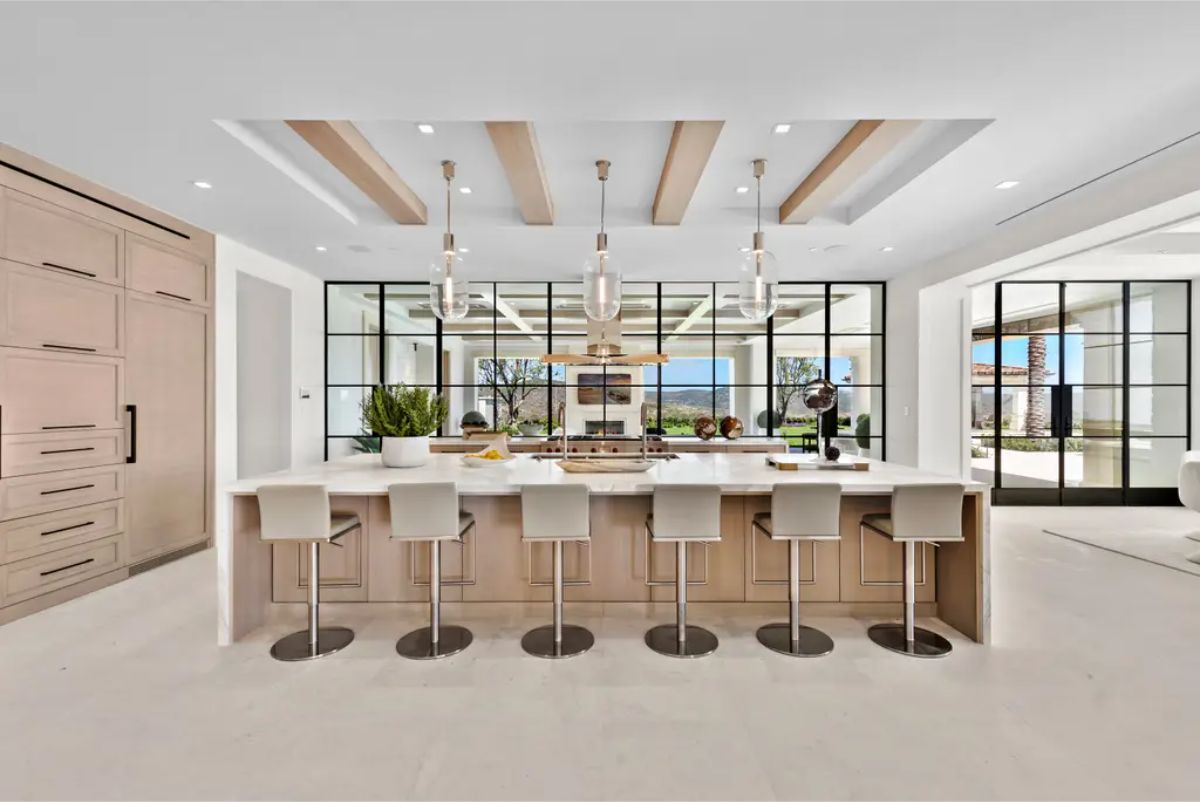 Spacious kitchen with a marble island, wooden accents, and modern lighting fixtures. 