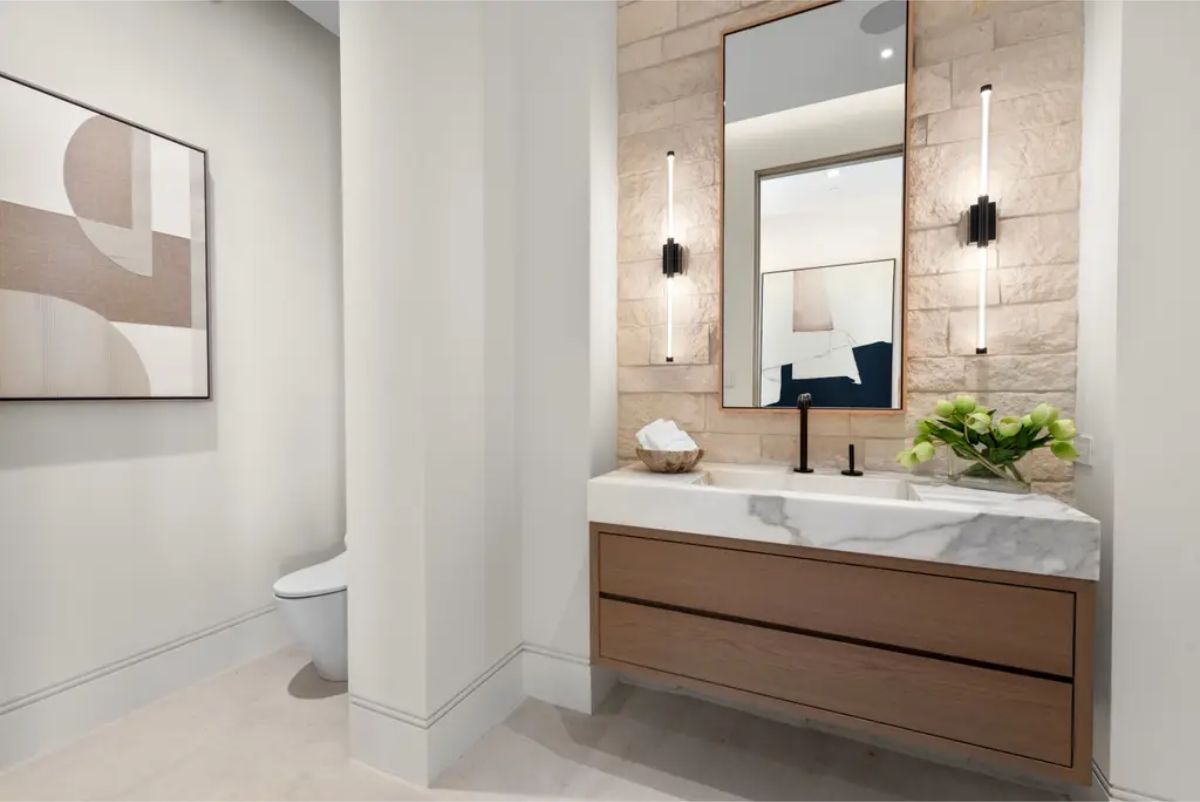 Stylish powder room with a marble countertop, textured wall, and minimalist decor. 