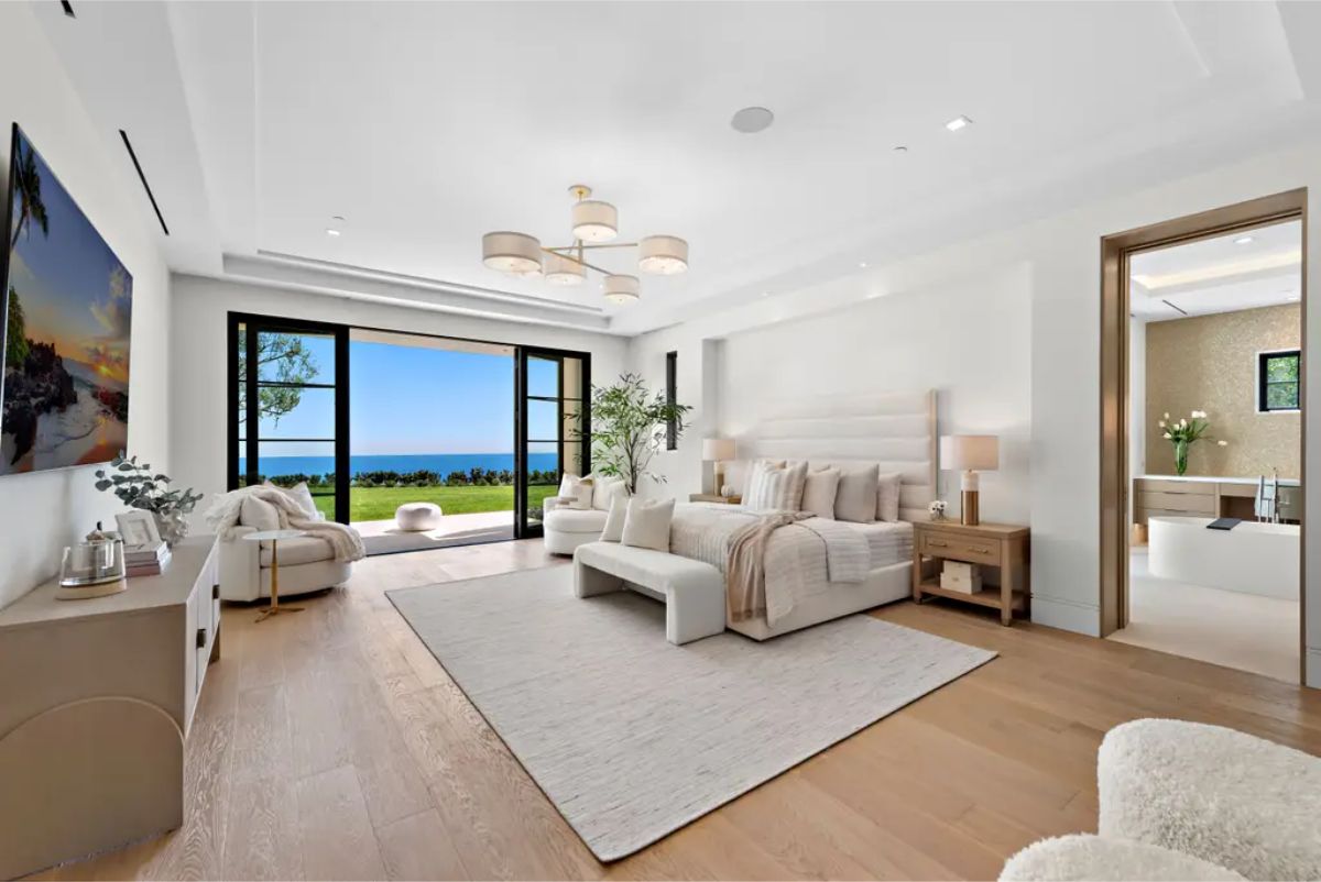 Luxurious bedroom with a neutral color palette, elegant chandelier, and an ocean view. 