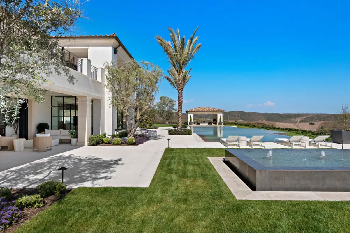 Beautifully landscaped backyard with a pool, water features, and a cabana for outdoor lounging. 