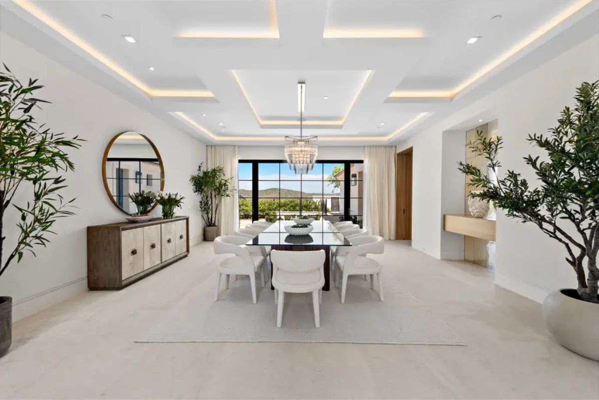 Modern dining room presents a sleek table, contemporary decor, and floor-to-ceiling windows with scenic views. 