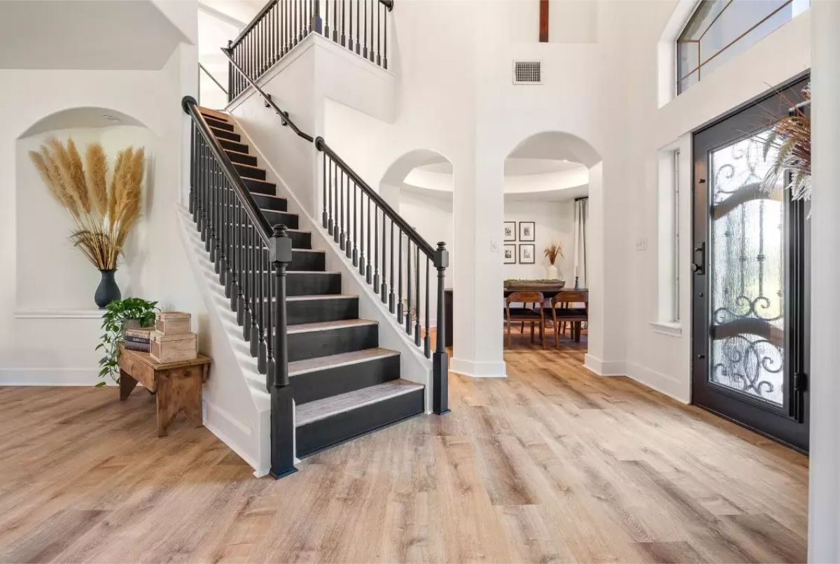 Entryway with high ceilings, light wood flooring, and a black iron staircase leading to the second floor.