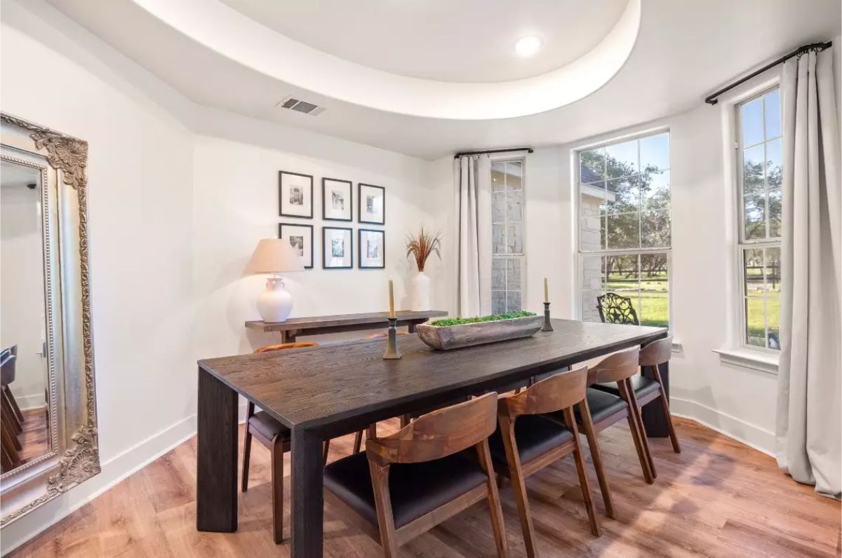 Dining room with a dark wooden table, matching chairs, and a curved ceiling detail.