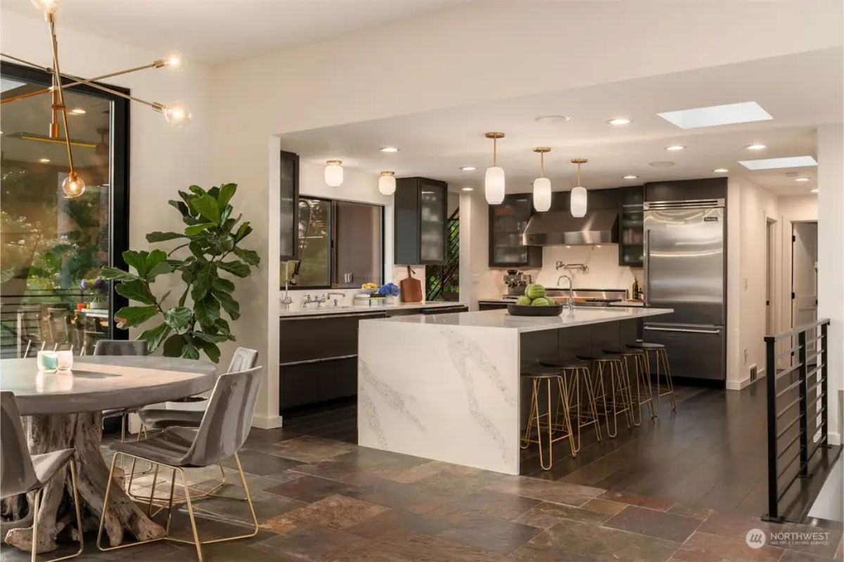 Sleek kitchen with a marble island, dark cabinetry, pendant lighting, and stainless steel appliances. 
