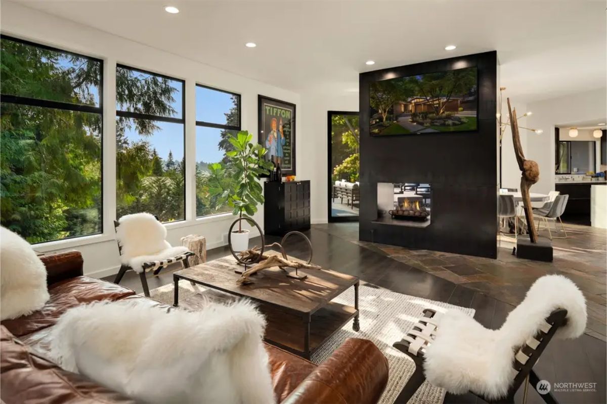 Cozy living room featuring a black fireplace, large windows, and a mix of modern and rustic decor. 
