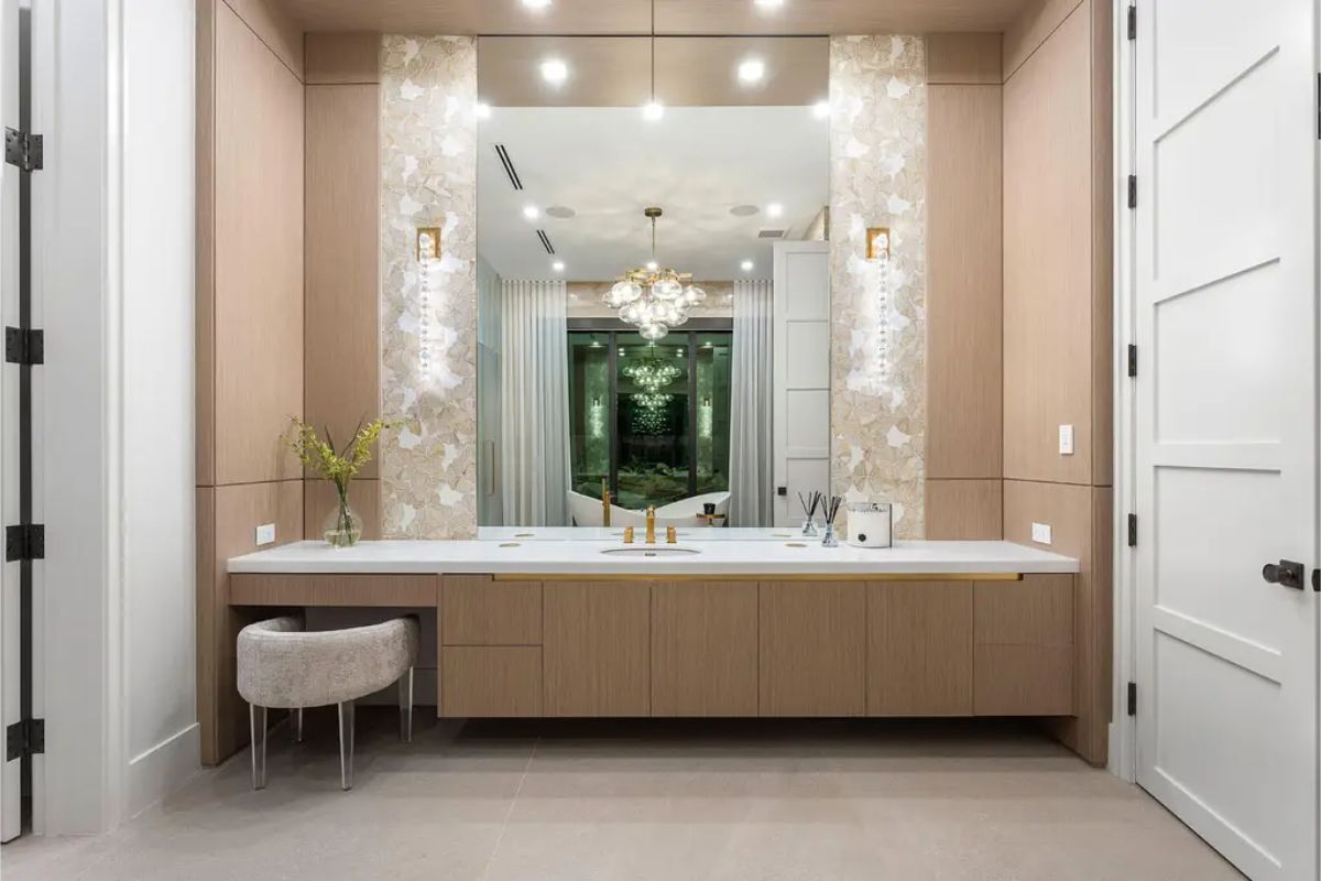 Elegant vanity area with dual sinks, floral decor, and a large mirror framed by artistic tile accents. 