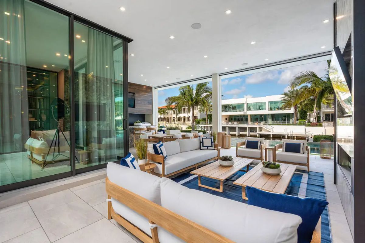 Open-air terrace with comfortable seating, wooden tables, and views of waterfront properties. 