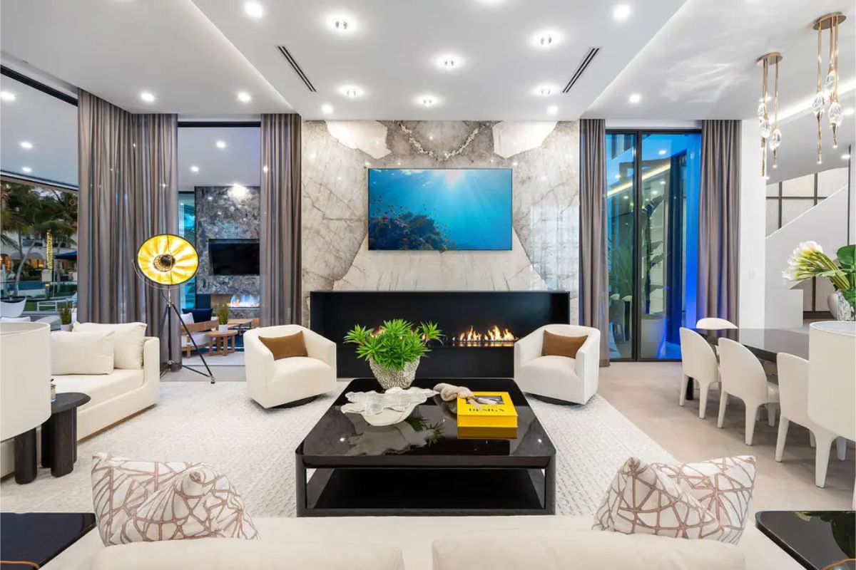 Luxurious living room featuring a sophisticated marble fireplace, large TV, and sleek modern furnishings. 