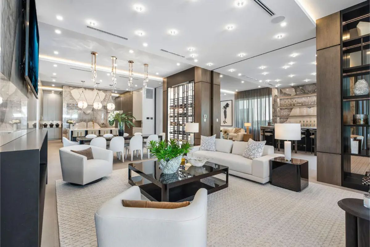 Open-concept living and dining space with elegant chandeliers, modern furniture, and a warm, inviting ambiance. 