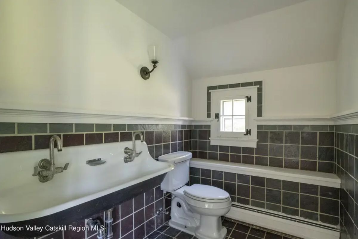Vintage-style bathroom includes a double sink with chrome faucets and a tiled half-wall.