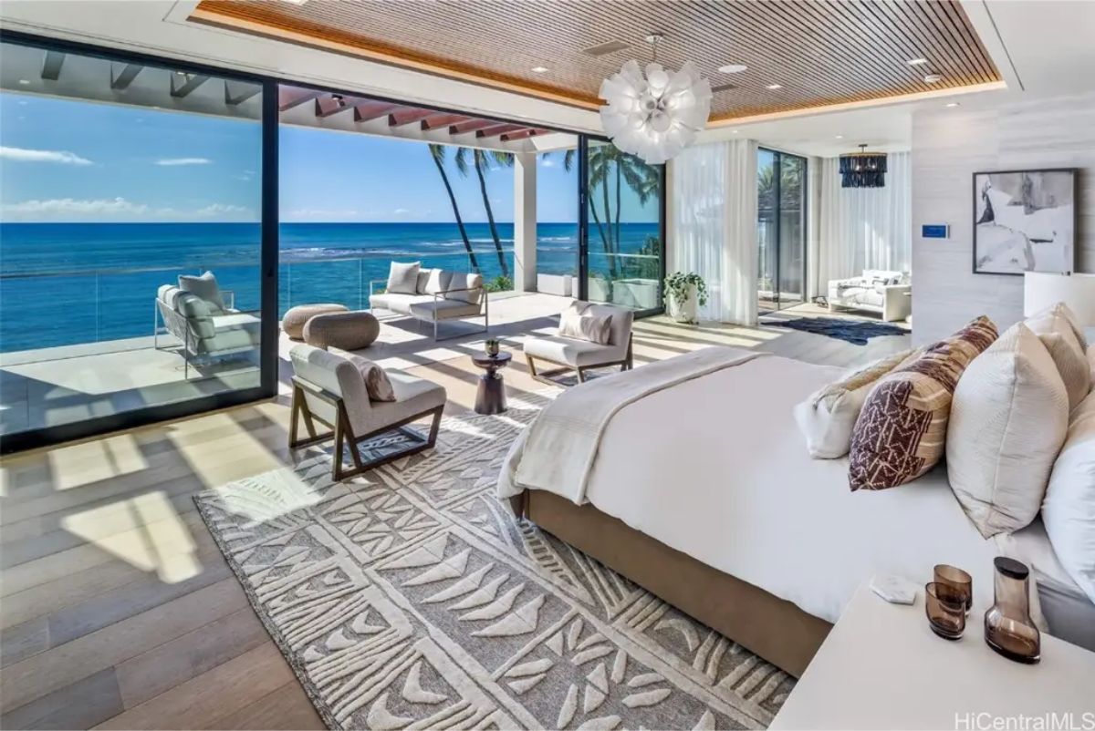 Oceanfront bedroom with floor-to-ceiling glass doors leading to a private terrace with breathtaking views. 