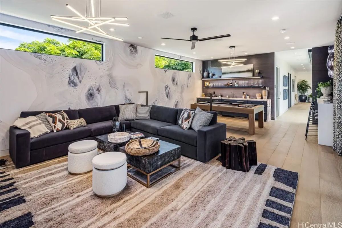 Entertainment lounge includes a large sectional sofa, textured accent wall, and an in-home bar for entertaining. 