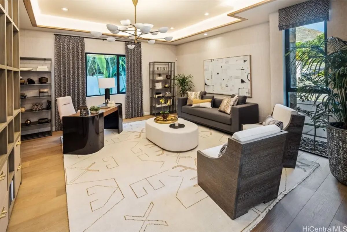 Stylish home office combines dark and light elements, featuring a geometric chandelier and elegant shelving. 