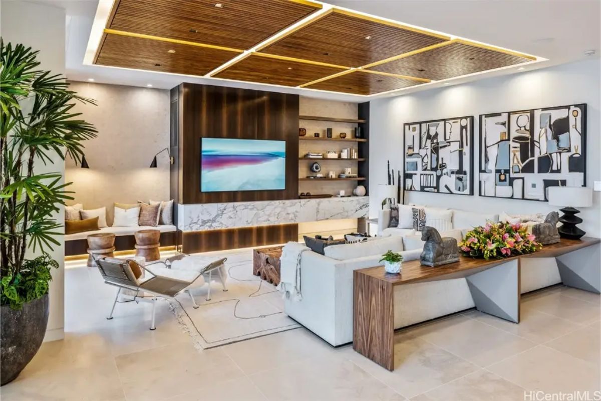 Cozy living room boasts wooden ceiling accents, a built-in fireplace, and a stylish marble entertainment center. 