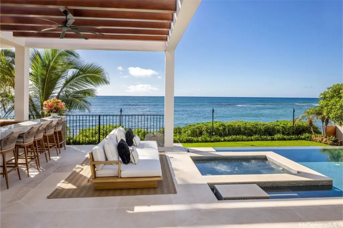 Cozy poolside sitting area with a built-in hot tub, tropical landscaping, and direct beach access. 