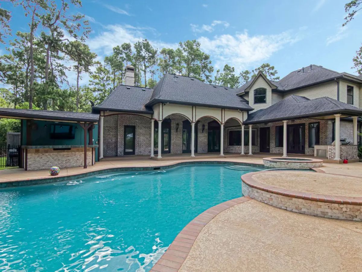 Outdoor space with a large swimming pool, spa, and covered patio.