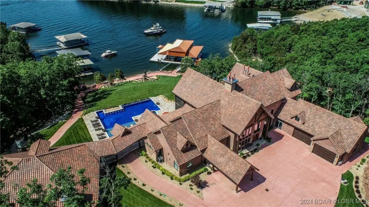 Lakeside property with a large home, private dock, and an in-ground swimming pool.