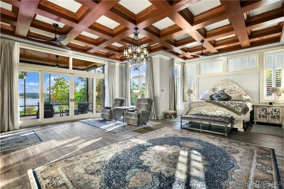 Spacious bedroom with a wood coffered ceiling and chandelier lighting.