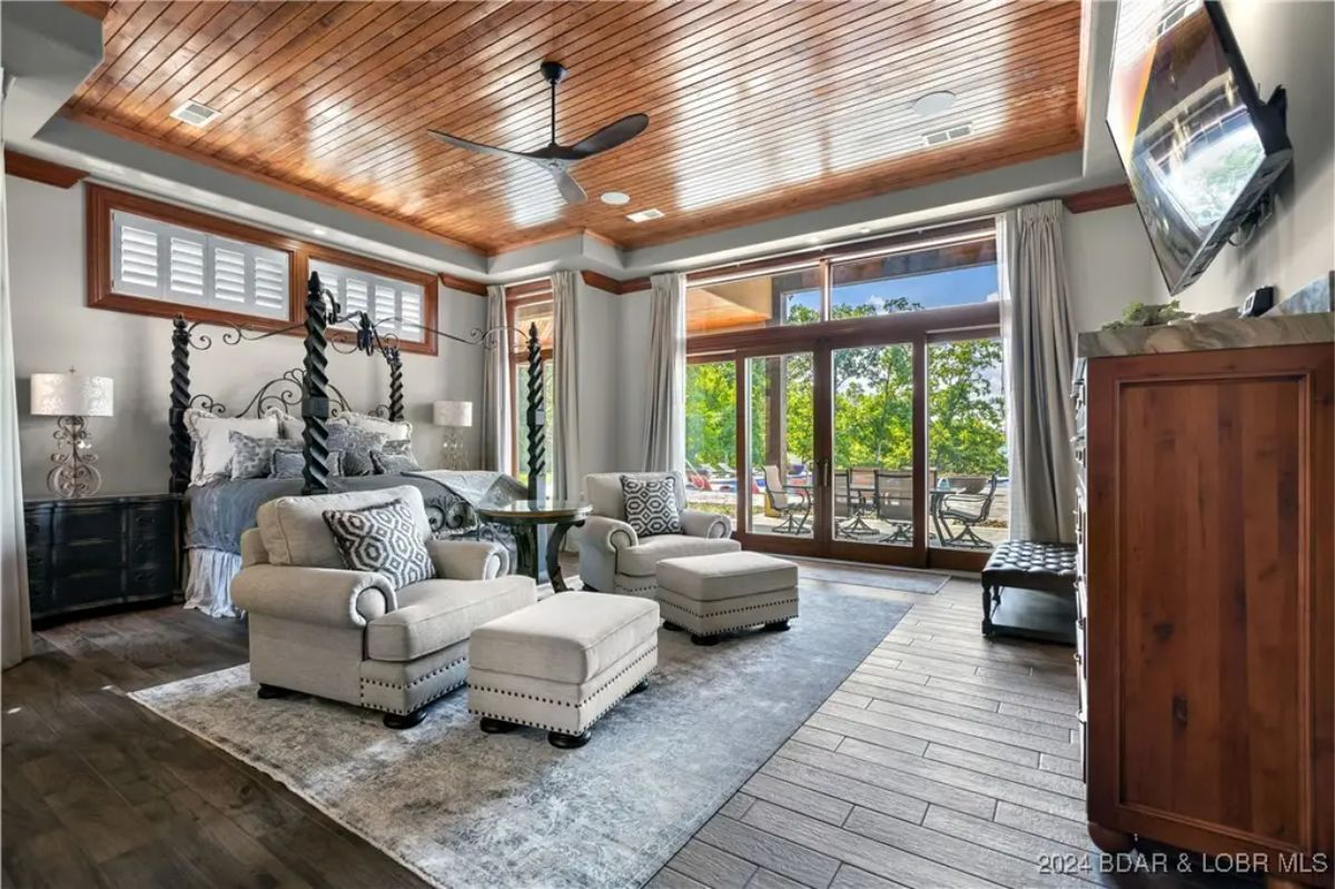 Large bedroom with wood-paneled ceiling and a private seating area.