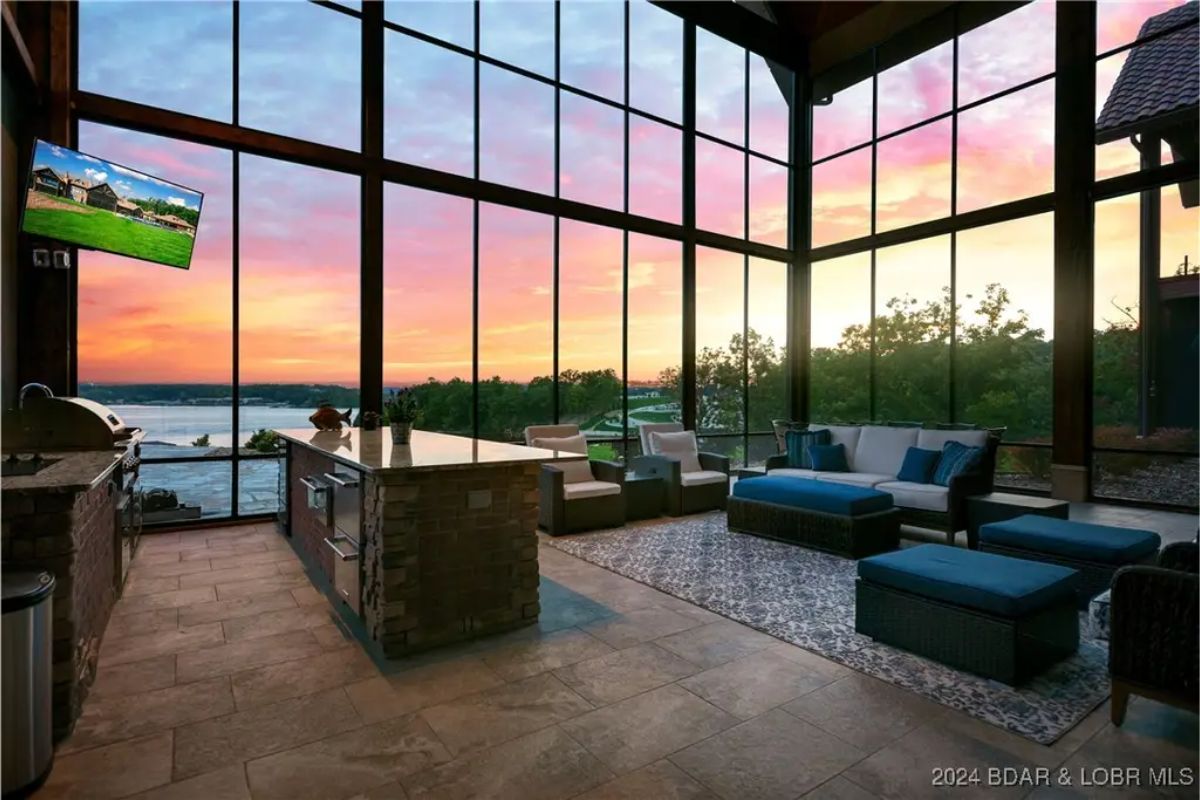 Enclosed sitting area with an outdoor kitchen and floor-to-ceiling glass walls.