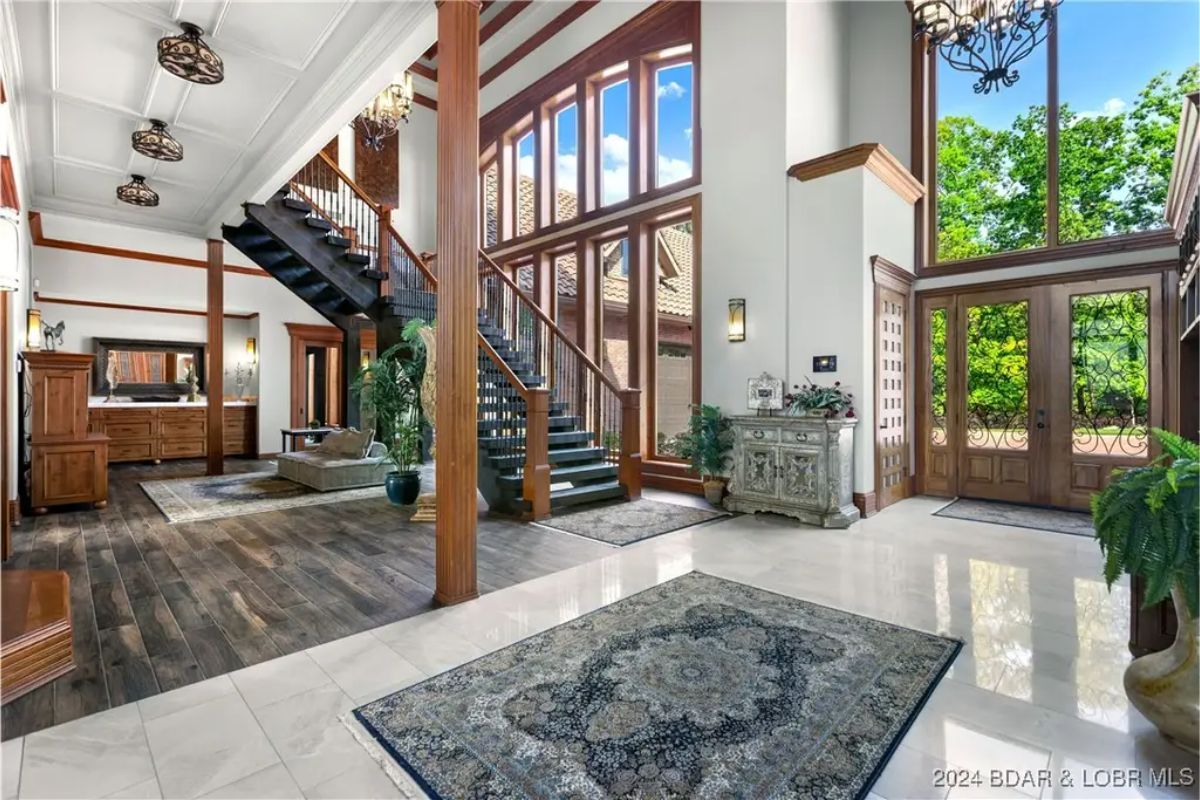 Two-story entrance with floor-to-ceiling windows and a mix of tile and wood flooring.