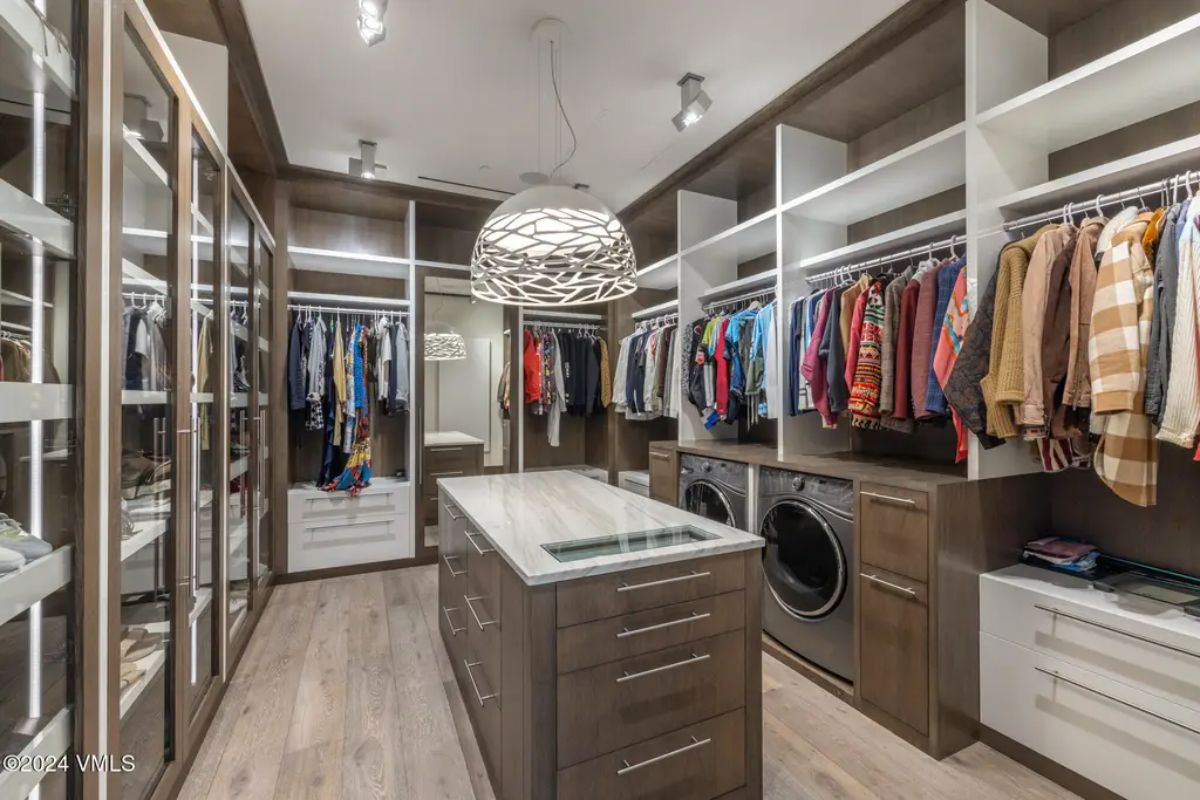 Walk-in closet with custom cabinetry with glass-front doors and open shelving.