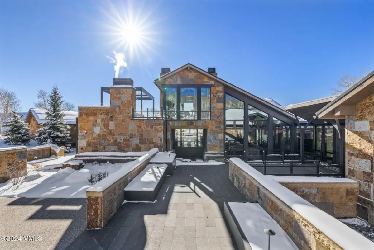 Contemporary stone-clad exterior with large floor-to-ceiling windows offering panoramic views.