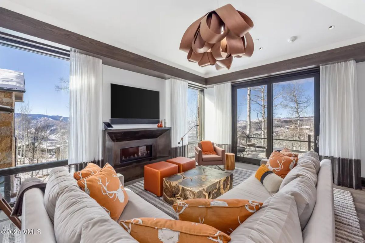 A sleek fireplace anchors the space beneath a sculptural wooden light fixture.