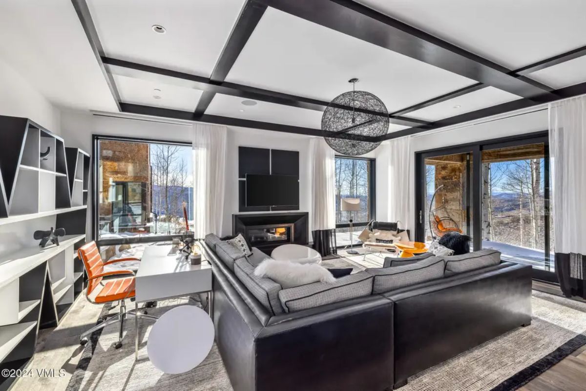 Large windows and glass doors showcase panoramic mountain scenery in a bright, open lounge.