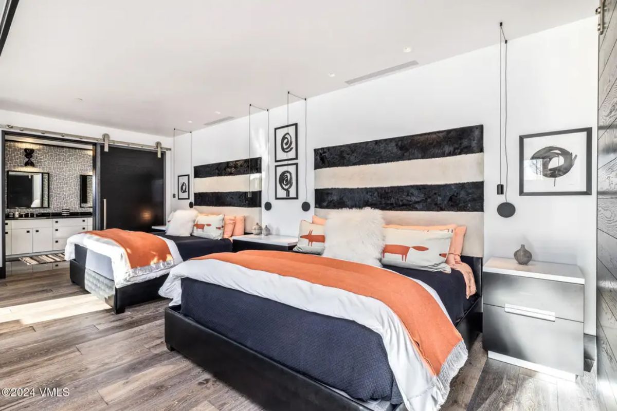 Two twin beds with black-and-white striped headboards, complemented by vibrant orange throws and fox-themed pillows.
