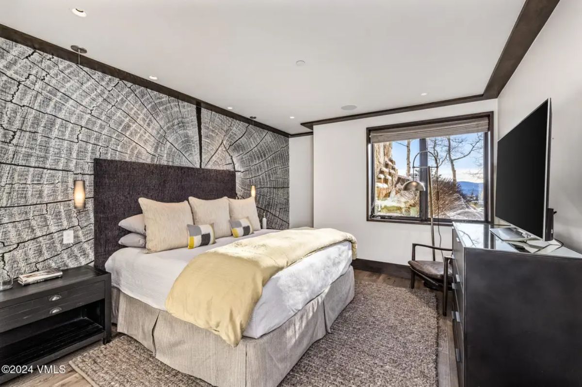 A striking accent wall resembling tree rings, complemented by a dark upholstered headboard.