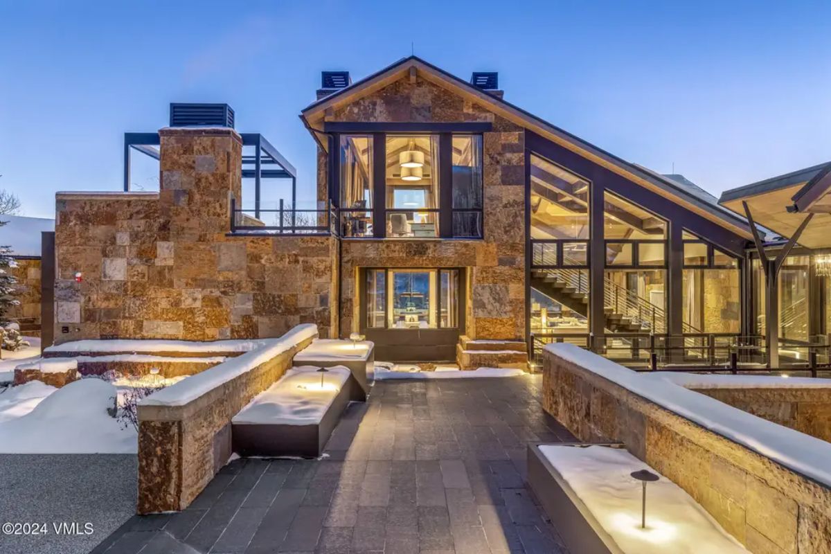 Modern residence featuring a stone façade, large glass windows, and an open terrace.