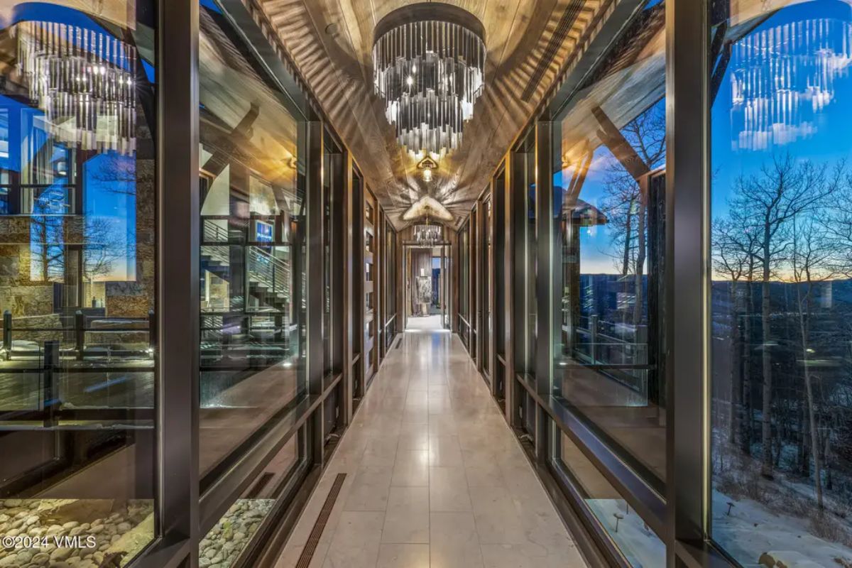 Striking hallway with floor-to-ceiling windows on both sides, offering panoramic mountain and forest views.