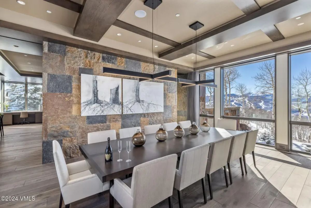 Long dining table with seating for twelve is framed by large windows offering expansive mountain views.