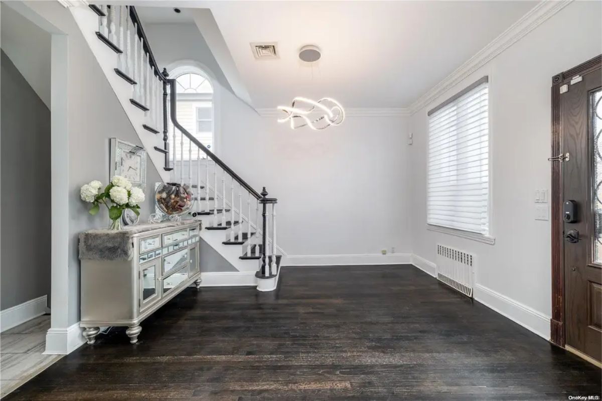 Dark hardwood flooring contrasts with white walls and staircase.