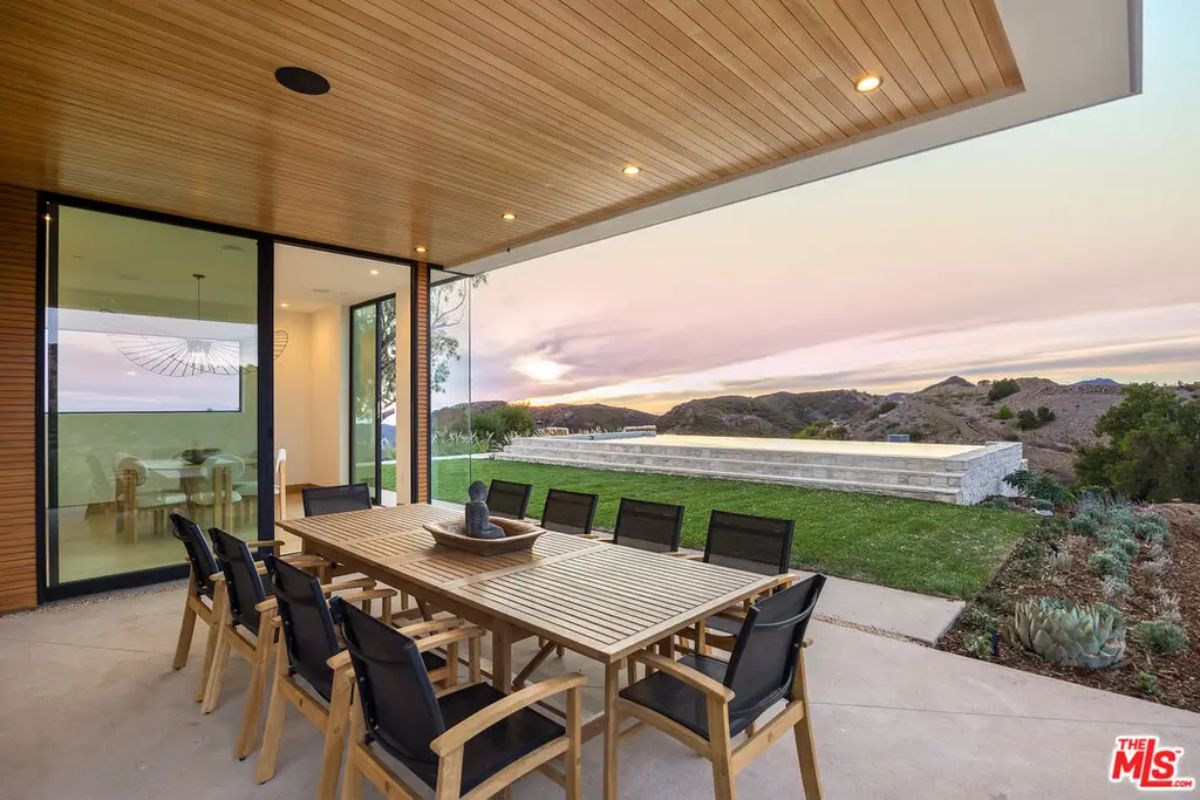 Outdoor dining space with a wooden ceiling and recessed lighting.