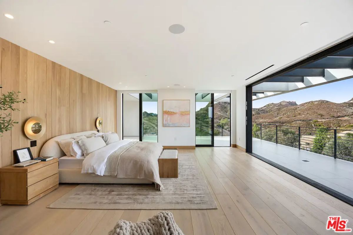 Large bedroom with a wood-paneled accent wall and minimalist furnishings.