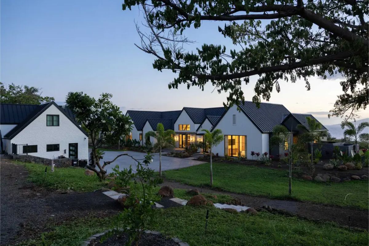 Black metal roofing contrasts with white brick exteriors and large windows.