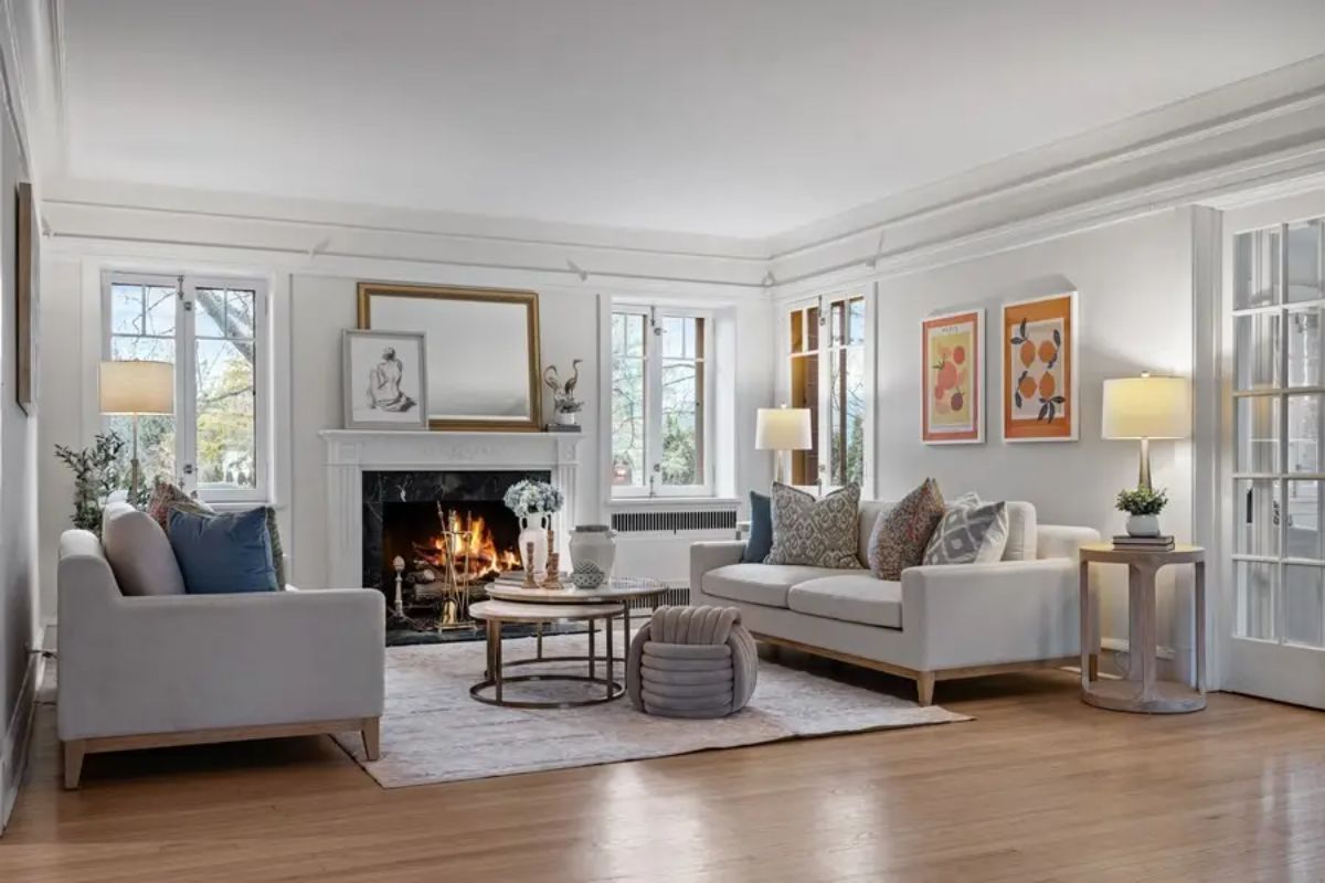 A living room with white walls and wood flooring has a fireplace as the focal point.