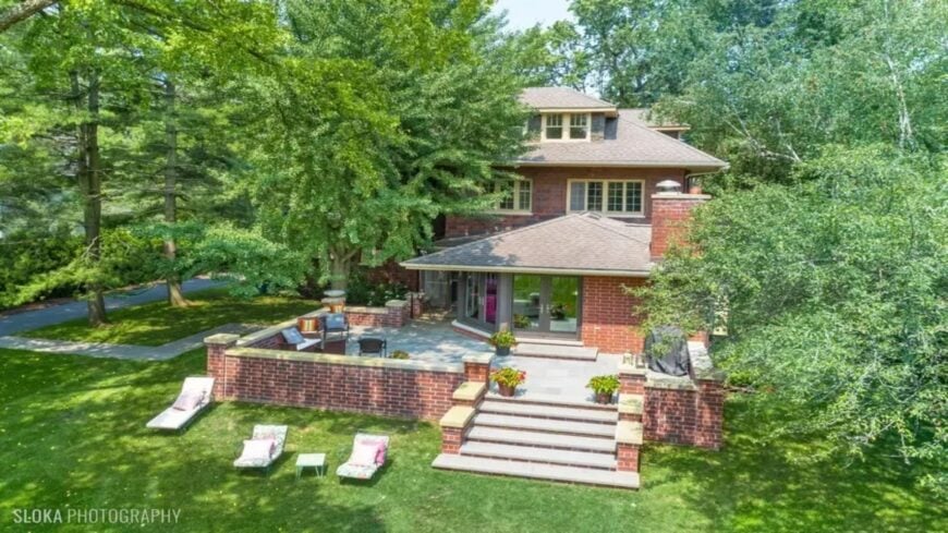 Current image: A multi-level brick patio with built-in seating extends from the back of the home.