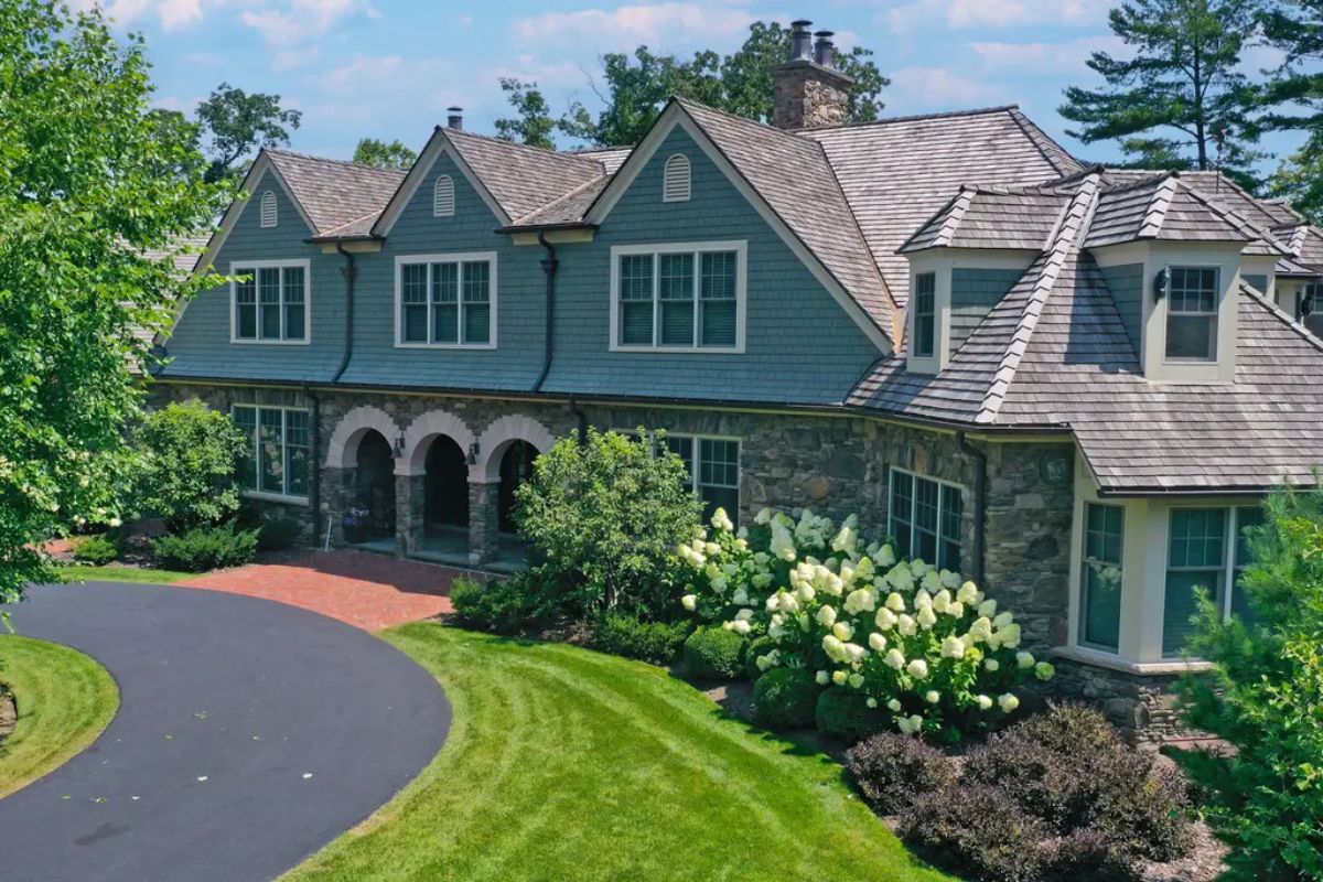 Two-story home features a combination of stone and shingle exterior with multiple gabled rooflines.
