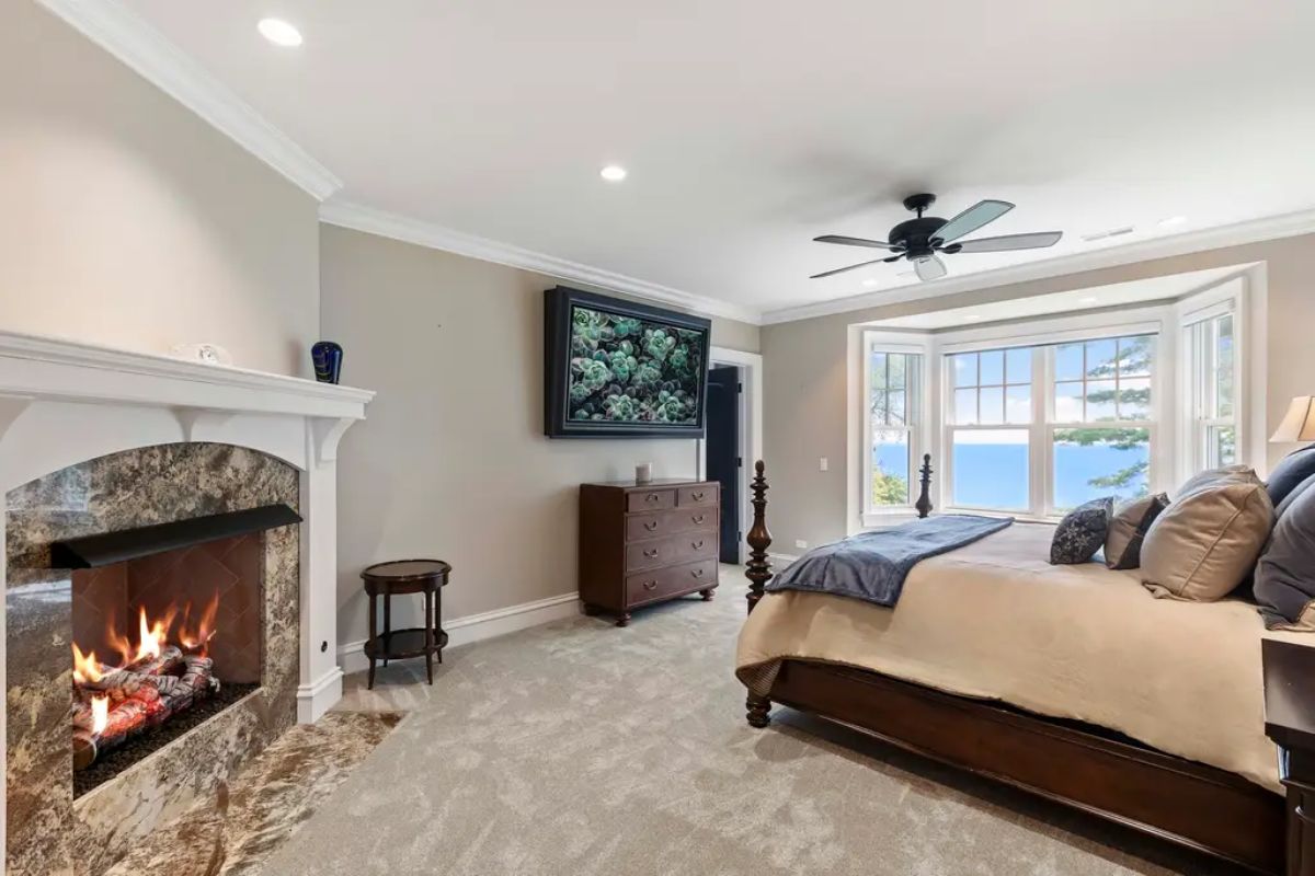 Cozy fireplace with a marble surround and a mounted flat-screen TV above a wooden dresser.