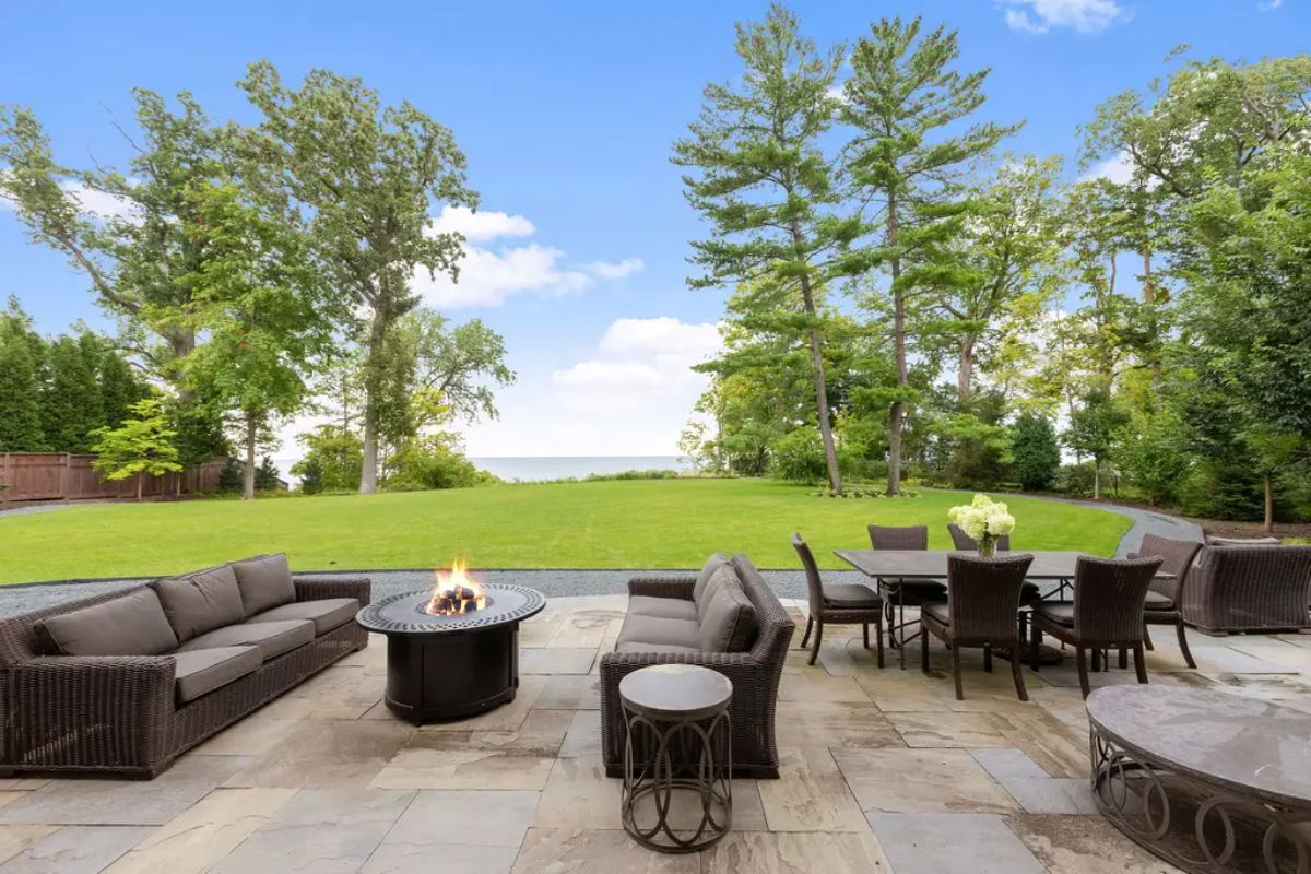 Stone patio with comfortable wicker seating arranged around a modern fire pit.