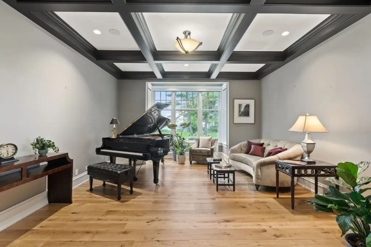 Bright music room featuring wide-plank hardwood flooring and a dark coffered ceiling with recessed lighting.