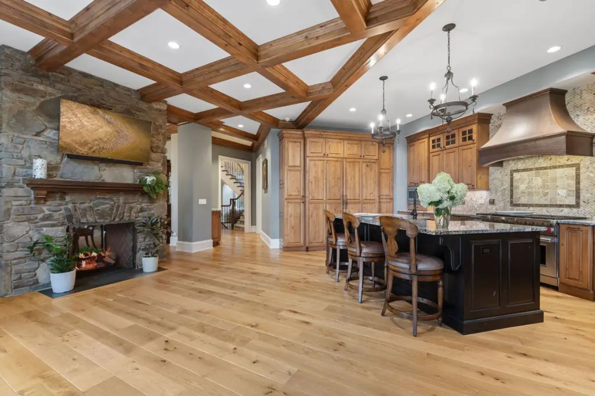 Open-concept kitchen features natural wood cabinetry, a large black island with granite countertops, and bar seating.