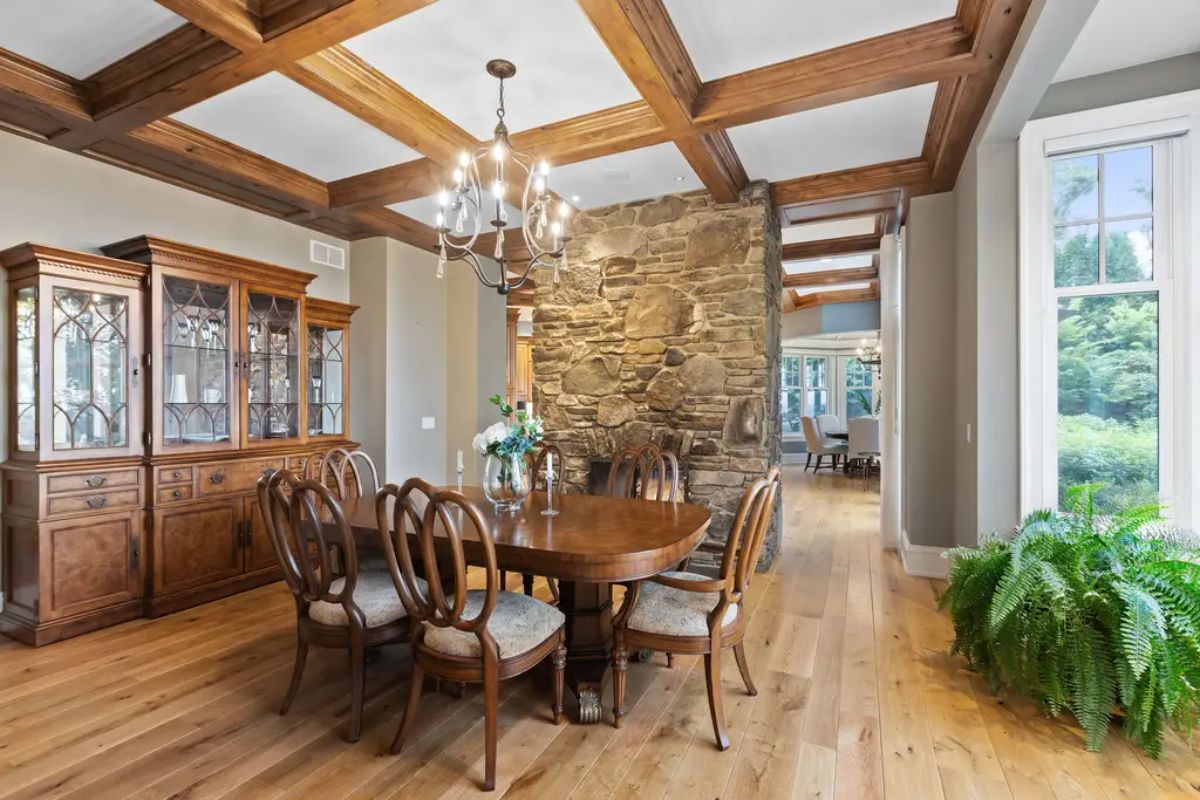 Natural light streaming through large windows, highlighting the warm wood-beamed ceiling.