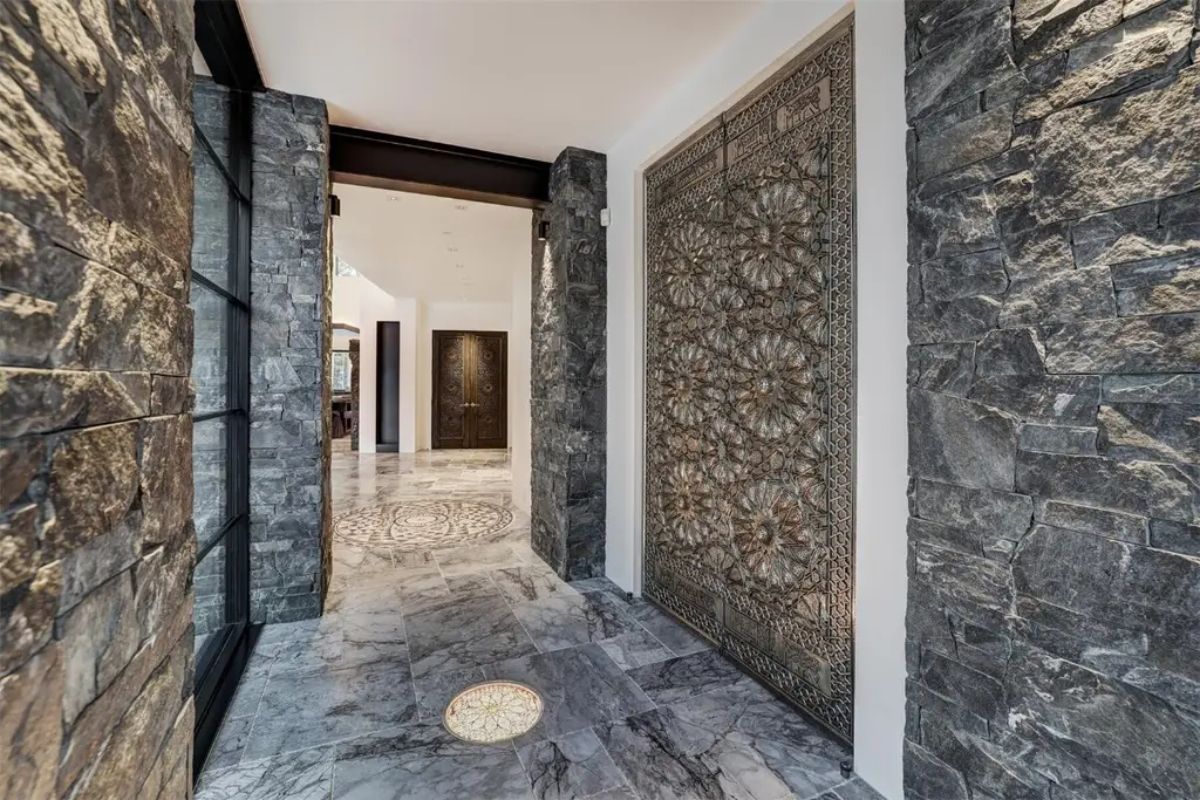Ornate metal door panels and textured stone walls give the corridor a luxurious and artistic ambiance. 