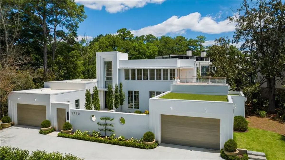 Front view of the house showcasing its geometric design, large garage doors, and well-manicured landscaping. 